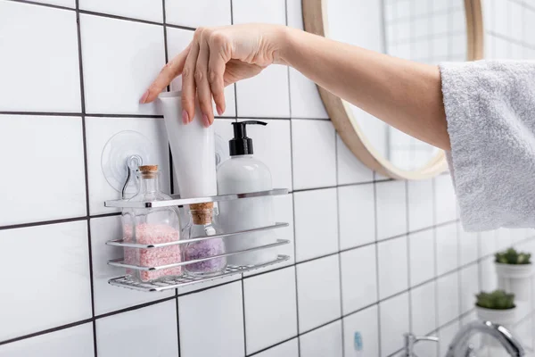 Vista cortada da mulher levando tubo com produto cosmético no banheiro — Fotografia de Stock