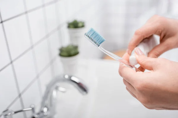 Vista recortada de la mujer sosteniendo cepillo de dientes con pasta de dientes - foto de stock