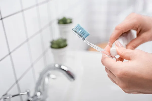 Vue recadrée de la femme tenant une brosse à dents avec du dentifrice — Photo de stock