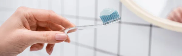 Vista recortada de la mujer sosteniendo cepillo de dientes con pasta de dientes en la mano, bandera - foto de stock