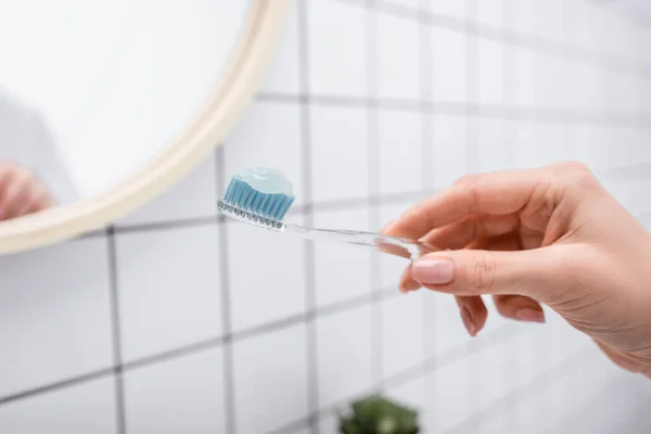 Vista ritagliata della donna che tiene lo spazzolino da denti con dentifricio in mano — Foto stock