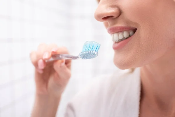 Partial view of cheerful woman smiling while holding toothbrush with toothpaste — Stock Photo