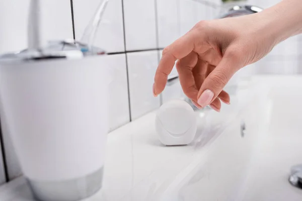 Cropped view of woman reaching plastic container with dental floss — Stock Photo