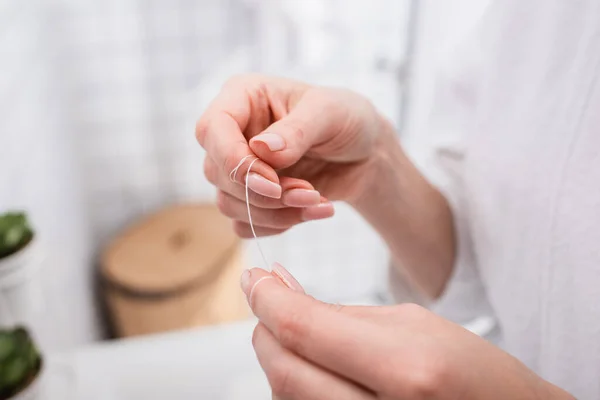 Primer plano de la mujer sosteniendo hilo dental en el baño - foto de stock