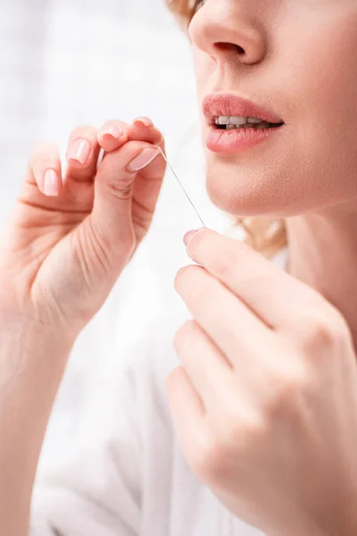 Vista cortada da mulher segurando fio dental nas mãos — Fotografia de Stock