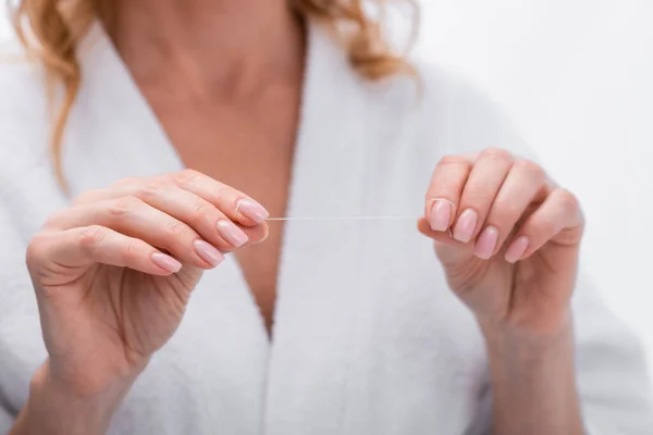 Vista recortada de la mujer en albornoz celebración de hilo dental en el baño - foto de stock