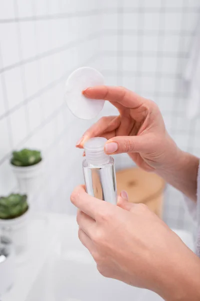 Partial view of woman holding toner and cotton pad in bathroom — Stock Photo