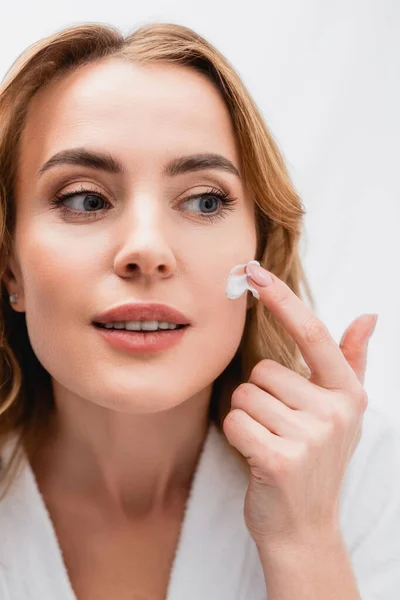 Femme appliquant la crème cosmétique sur le visage dans la salle de bain — Photo de stock
