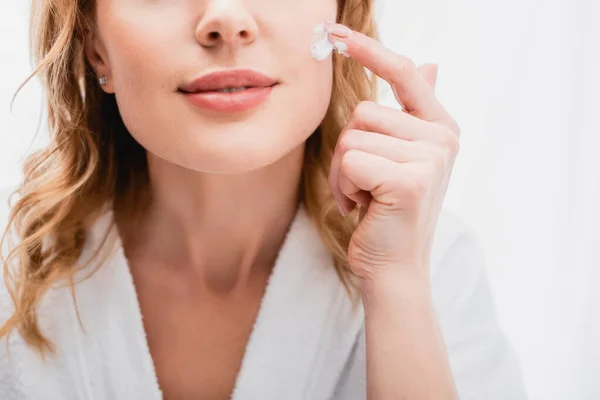 Vue recadrée de la femme appliquant la crème cosmétique sur le visage dans la salle de bain — Photo de stock