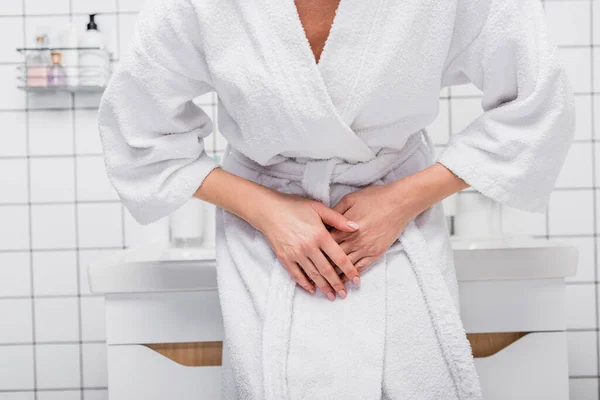 Partial view of woman in bathrobe suffering from abdomen pain in bathroom — Stock Photo