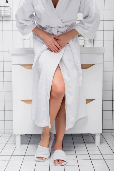 Cropped view of woman in bathrobe suffering from abdomen pain in bathroom — Stock Photo