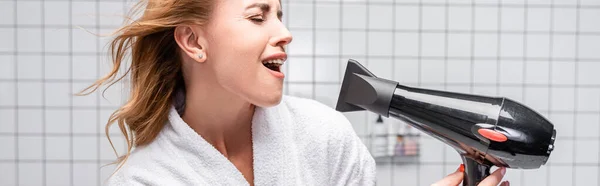 Mulher de roupão branco secando o cabelo brilhante e cantando no banheiro, banner — Fotografia de Stock