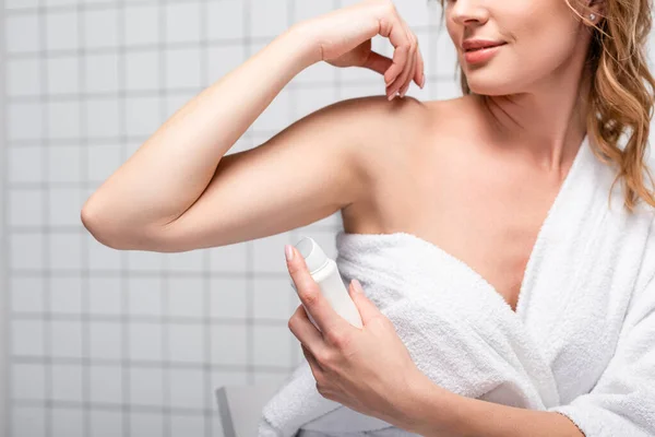 Vista recortada de la mujer en toalla blanca aplicando desodorante en el baño - foto de stock