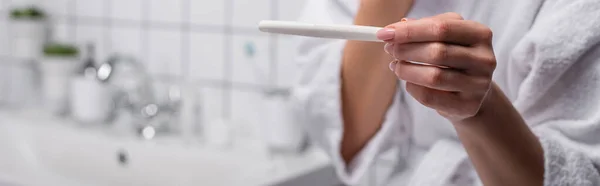 Vista parcial de la mujer que sostiene la prueba de embarazo en el baño - foto de stock