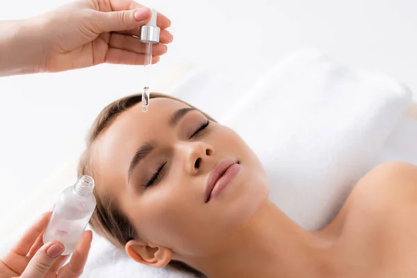 Kosmetikerin hält Pipette und appliziert Serum auf Gesicht der Frau im Wellness-Salon — Stockfoto