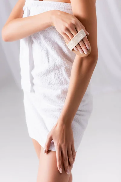 Partial view of woman exfoliating skin with brush on white — Stock Photo