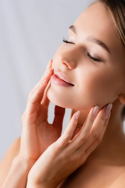 Young woman with closed eyes touching face on white — Stock Photo