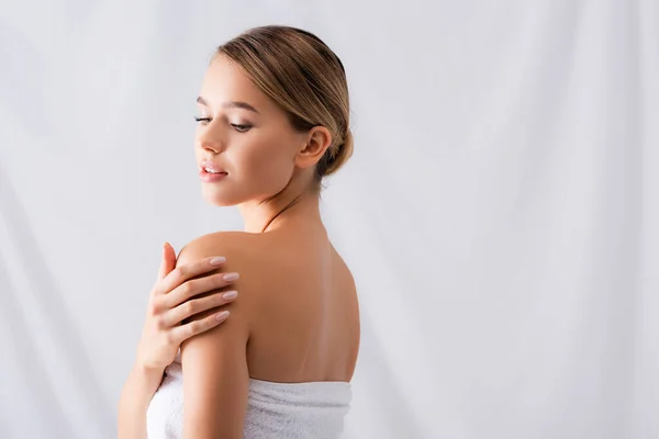 Junge Frau berührt nackte Schultern auf Weiß — Stockfoto