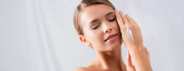 Sensual mujer joven con los ojos cerrados y crema en la mano, bandera - foto de stock