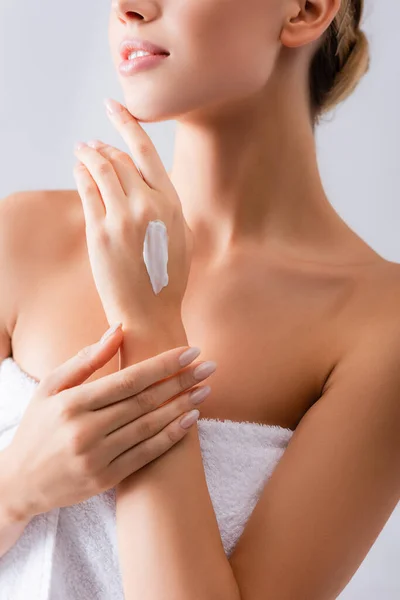 Partial view of young woman with bare shoulders and cream on hand on white — Stock Photo