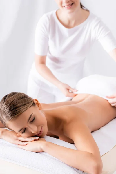 Masseur adjusting towel on beautiful client lying on massage table — Stock Photo