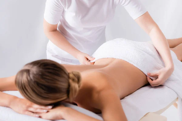 Cropped view of masseur adjusting towel on client lying on massage table — Stock Photo