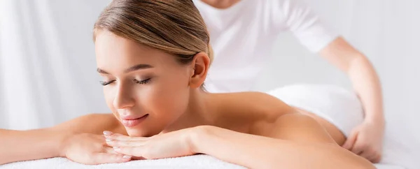 Young woman lying on massage table near masseur on blurred background, banner — Stock Photo