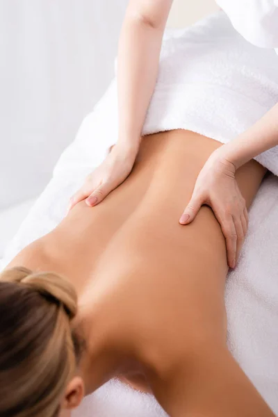 Cropped view of masseur massaging back of client lying on massage table — Stock Photo
