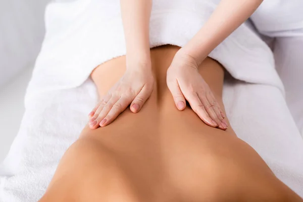 Partial view of masseur massaging back of client lying on massage table — Stock Photo