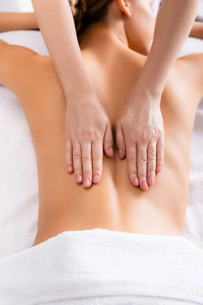 Vista cortada do massagista massageando cliente deitado na mesa de massagem — Fotografia de Stock