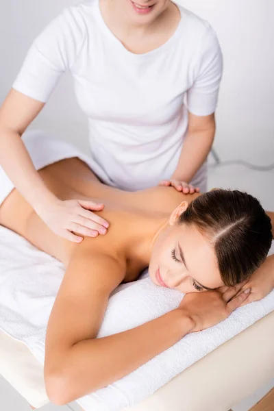 Lächelnder Masseur massiert Rücken des Kunden auf Massagetisch — Stockfoto