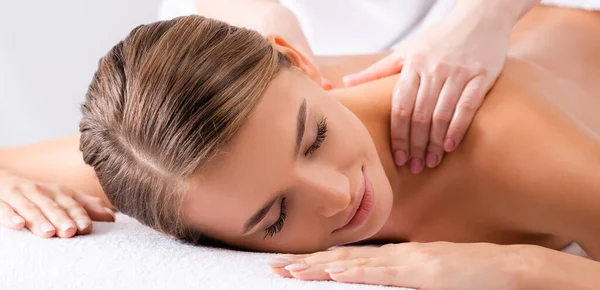 Masseur massaging pleased woman on massage table in spa salon, banner — Stock Photo