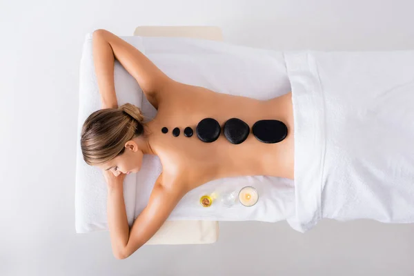 Vista superior da jovem mulher recebendo massagem de pedra quente no salão de spa — Fotografia de Stock