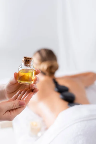 Ausgeschnittene Ansicht des Masseurs, der eine Flasche mit Öl in der Nähe des Kunden hält — Stockfoto