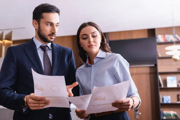 Arabian businessman pointing at document near young business partner — Stock Photo