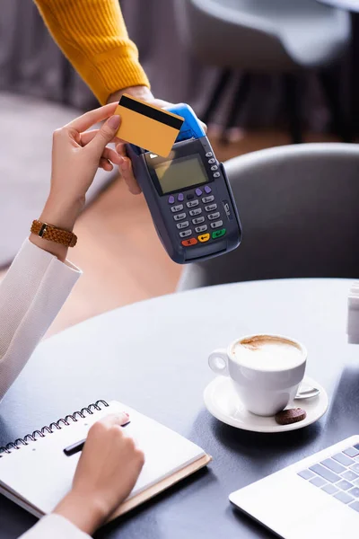 Vista recortada de freelancer con tarjeta de crédito cerca de terminal de pago un mano de camarero - foto de stock