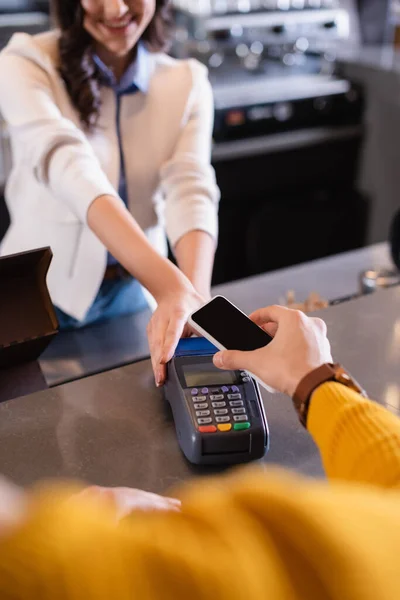 Vue recadrée de l'homme payant avec smartphone près de barman avec terminal de paiement dans le restaurant — Photo de stock