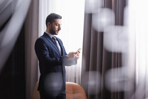Arabischer Geschäftsmann nutzt Smartphone in modernem Restaurant — Stockfoto