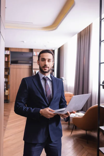 Jeune homme d'affaires arabe tenant un ordinateur portable et regardant la caméra dans le restaurant — Photo de stock