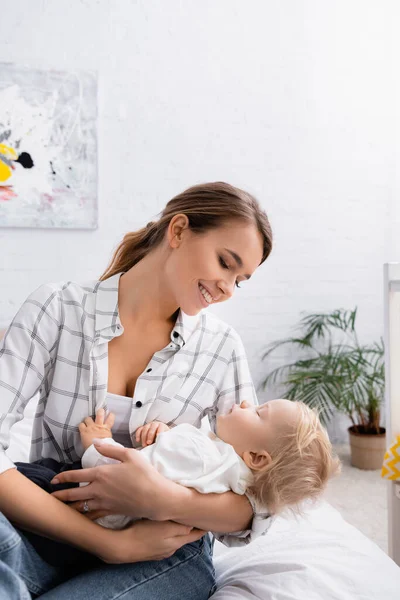Счастливая мать убаюкивает малыша сына в спальне — Stock Photo