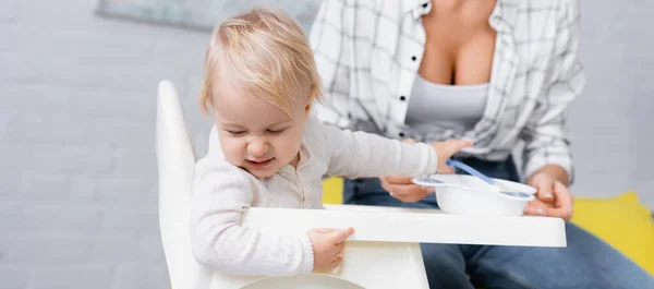 Frowning child turning away from food near mother on blurred background, banner — Stock Photo
