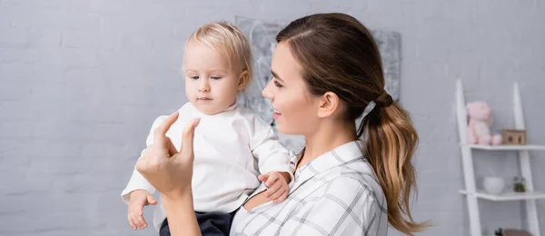 Smiling mother showing small amount gesture while holding little son, banner — Stock Photo
