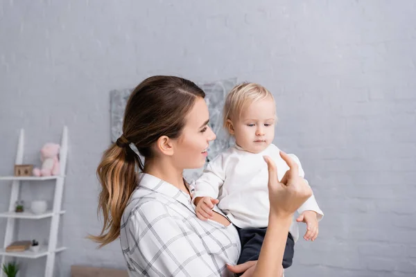 Smiling mother showing small quantity gesture to toddler son — Stock Photo