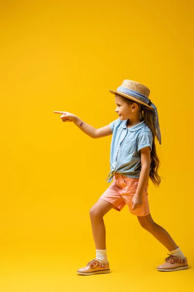 Full length of happy kid with temporary tattoo on hand pointing with finger on yellow — Stock Photo