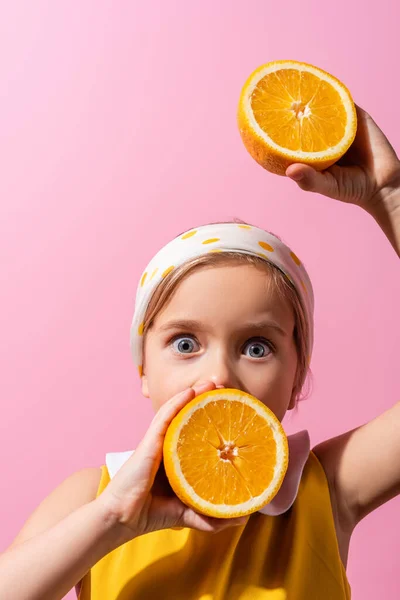 Shocked girl in headscarf covering mouth with orange half isolated on pink — Stock Photo
