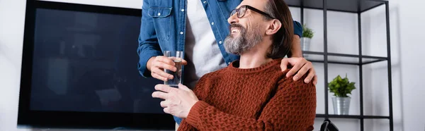 Man giving glass of water to happy father, banner — Stock Photo