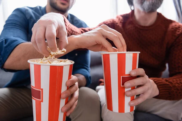 Vista parcial de padre e hijo con cubos de palomitas de maíz, fondo borroso - foto de stock