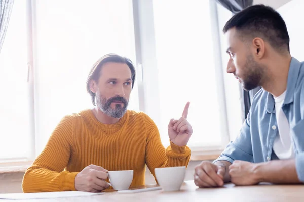 Ernster Mann zeigt mit dem Finger, während er mit hispanischem Sohn in der Küche spricht — Stockfoto