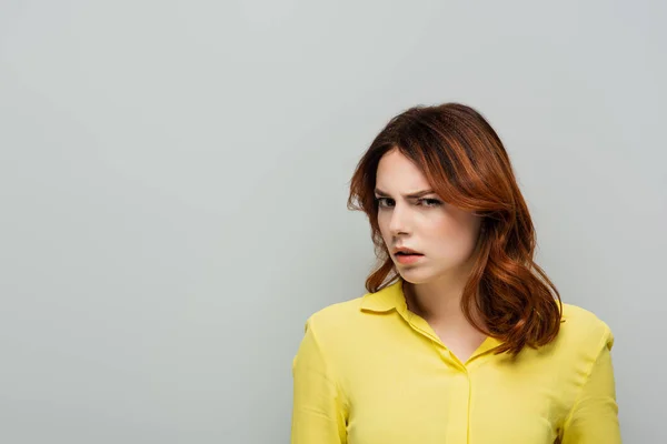 Mujer desconfiada en blusa amarilla mirando a la cámara aislada en gris - foto de stock