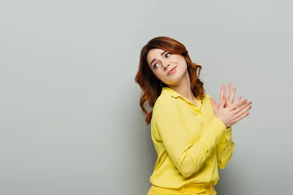 Skeptical woman rubbing hands while looking back grey — Stock Photo